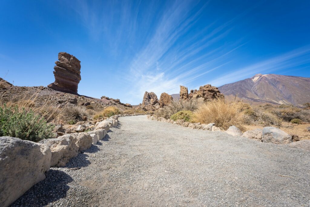 Wanderweg mit Felsformationen im Nationalpark Teide unter blauem Himmel auf Teneriffa, Kanarische Inseln.