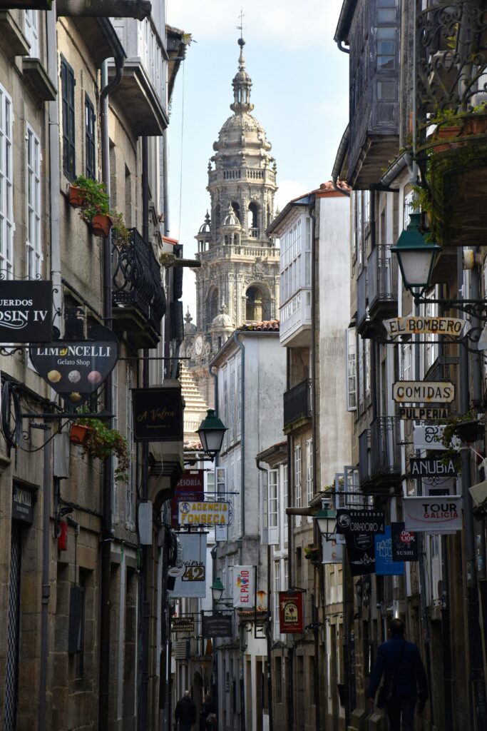 Enge Altstadtgasse mit Ladenschildern in Santiago de Compostela und Blick auf die Kathedrale, Galicien, Spanien.