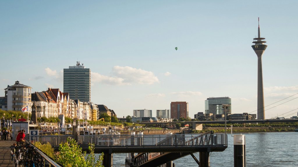 Skyline von Düsseldorf mit dem Rheinturm und der Rheinpromenade an einem sonnigen Tag.