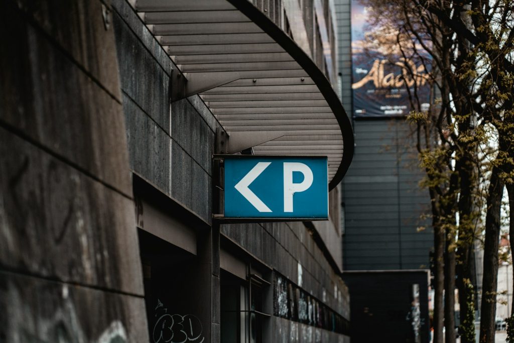 Blaues Parkhaus-Schild mit Pfeil an einer Gebäudefassade in der Stadt.