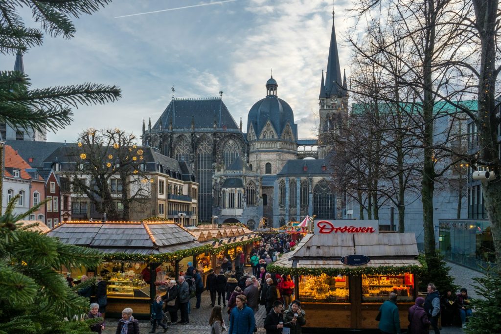 Weihnachtsmarkt vor dem Aachener Dom mit Besuchern und beleuchteten Marktständen.