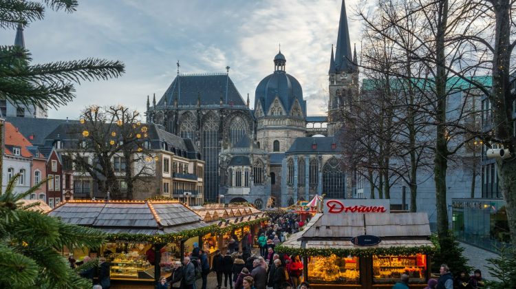 Weihnachtsmarkt vor dem Aachener Dom mit Besuchern und beleuchteten Marktständen.