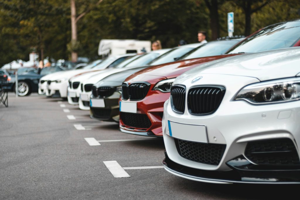 Mehrere Autos parken nebeneinander auf einem Parkplatz mit markierten Stellplätzen.