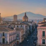 Blick über die Altstadt von Catania mit barocken Gebäuden, einer Kirchenkuppel und dem Ätna im Hintergrund.