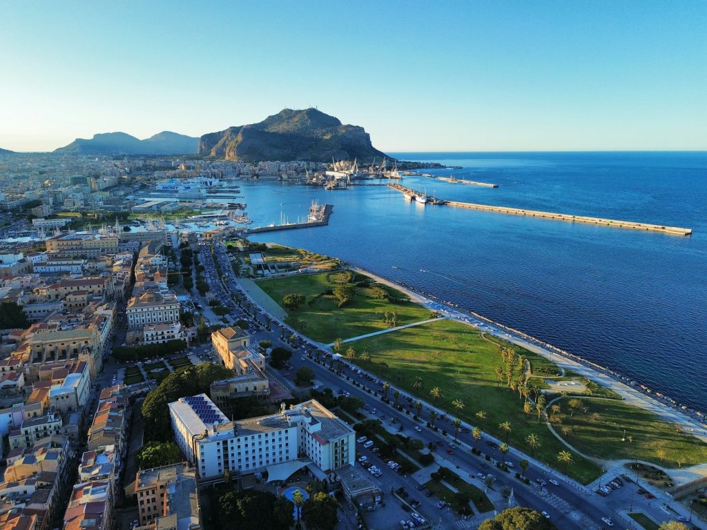 Luftaufnahme von Palermo mit Hafen, Küstenpromenade, Grünflächen und dem Meer. 