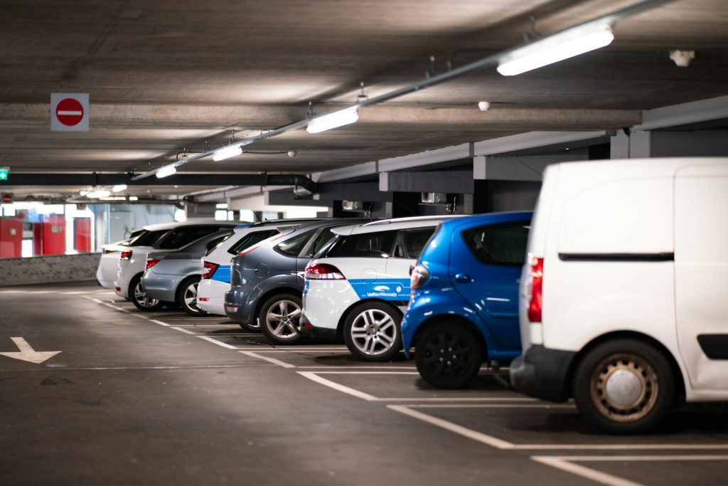 Tiefgarage mit geparkten Fahrzeugen in einer Reihe unter Neonbeleuchtung und Verbotsschild.