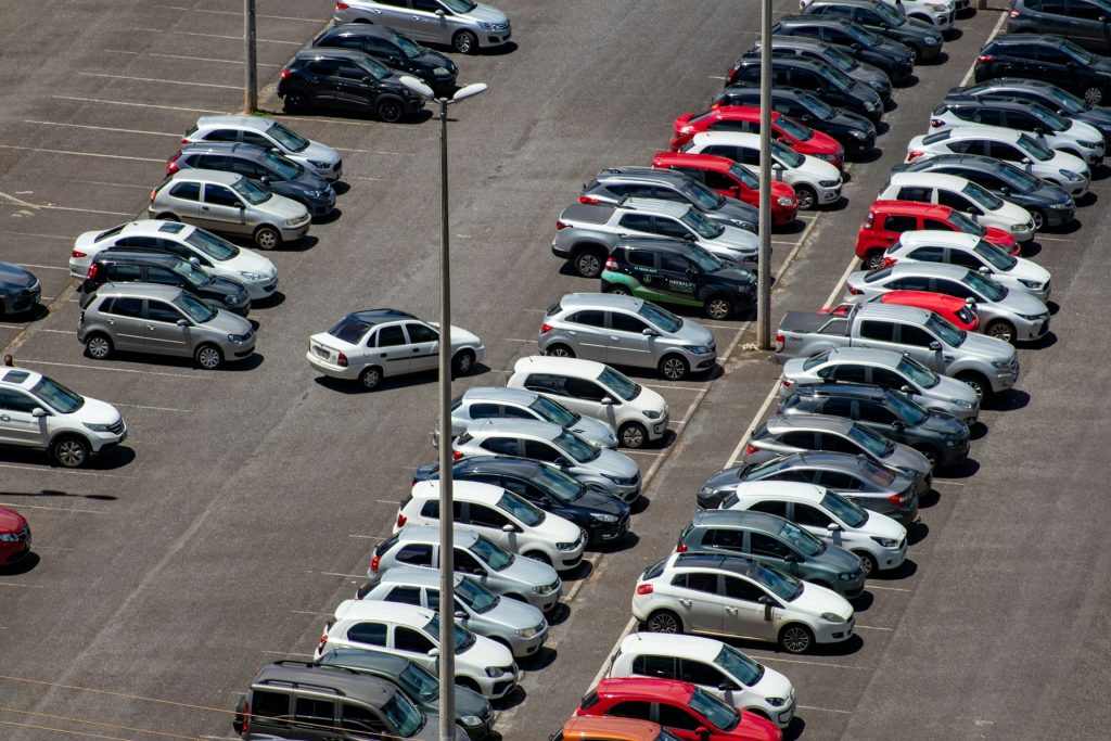 Großer Parkplatz mit dicht gereihten Fahrzeugen aus der Vogelperspektive bei Tageslicht.