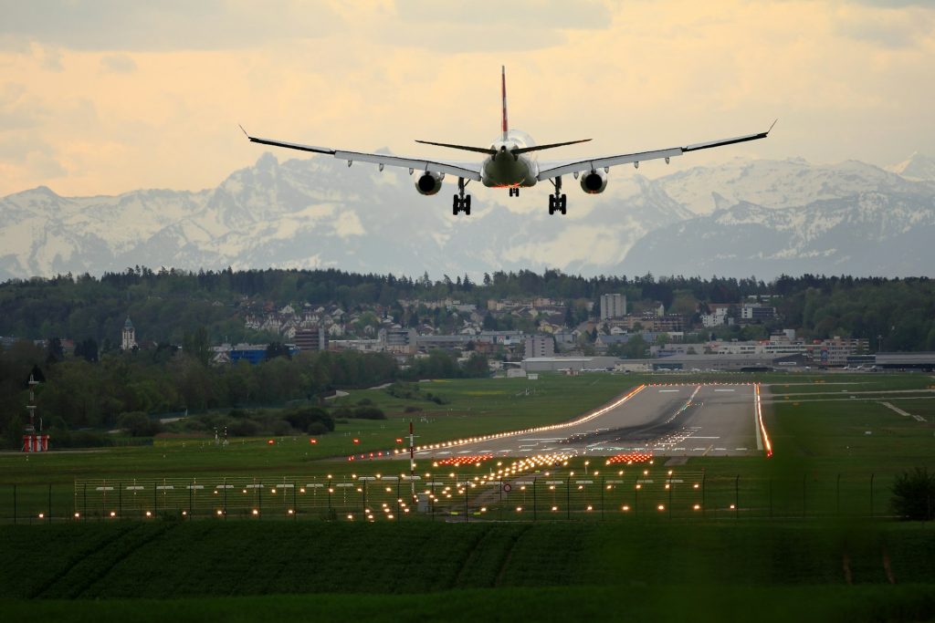 Passagierflugzeug im Landeanflug auf eine beleuchtete Landebahn in der Abenddämmerung.