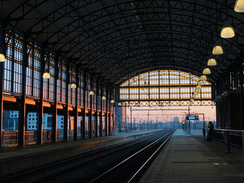 Leerer Bahnsteig eines historischen Bahnhofs mit gusseisernem Bogendach bei Sonnenuntergang.