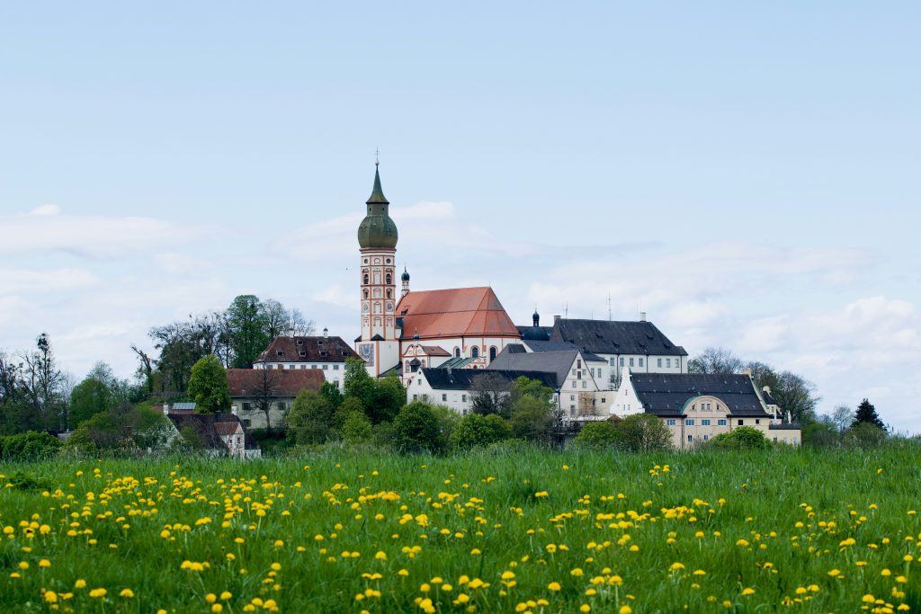 Kloster Andechs auf einem Hügel mit barocker Klosterkirche und blühender Frühlingswiese im Vordergrund.