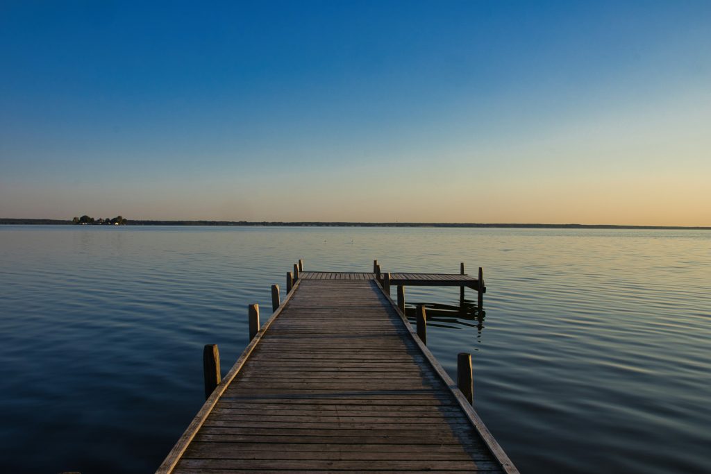 Hölzerner Anlegesteg auf dem Steinhuder Meer bei Sonnenuntergang mit ruhigem Wasser und klarem Himmel.