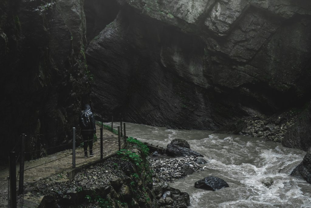 Wanderer auf einem schmalen Felsweg entlang des tosenden Flusses in der Partnachklamm bei Garmisch-Partenkirchen.